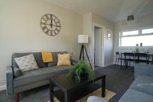 a living room with a couch and a clock on the wall at McCracken House in Uddingston