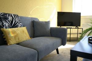 sala de estar con sofá azul y TV en McCracken House en Uddingston