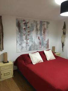 a bedroom with a red bed with two white pillows at Xalpen B&B in Puerto Natales