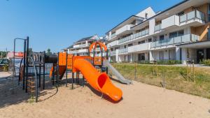 a playground with an orange slide in front of a building at Apartament Baltic Garden&Sztutowo in Sztutowo