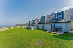 a row of houses on a lawn near the ocean at 18 - 3 Bedroom Cottage - LP in Pwllheli