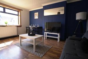 uma sala de estar azul com um sofá e uma televisão em Sauchie House 