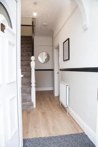 a hallway with white walls and a staircase with wood floors at 8 Karslake Road in Wallasey