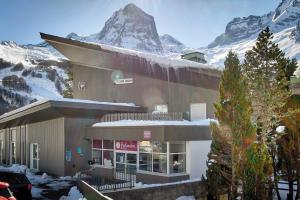 a building with a snow covered mountain in the background at Belambra Clubs Gourette - Lou Sarri in Gourette +36 photos