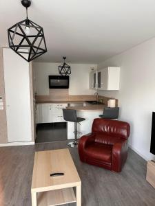 ein Wohnzimmer mit einem Ledersessel und eine Küche in der Unterkunft Colombes Proche La Défense et Paris, 1 chambre, SDB, wifi et cuisine équipée in Colombes