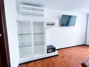 uma prateleira de livros brancos com uma televisão num quarto em Apartamentos Turisticos In Di Morgan's Canon em San Andrés