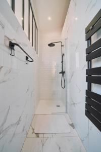 y baño con ducha y paredes de mármol blanco. en Villa Bewick-Loft Architecte, en Saint-Valery-sur-Somme