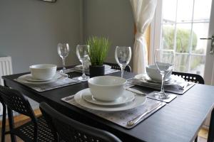 una mesa negra con platos y copas de vino. en Ravenswood House en Glenrothes