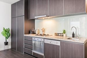 a kitchen with a sink and a stove top oven at Rooftop Pool 2BR Apt at Marvel Stadium with Free Parking in Melbourne