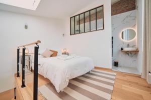 a white bedroom with a bed and a staircase at Villa Bewick-Loft Architecte in Saint-Valery-sur-Somme