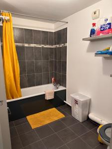 ein Badezimmer mit einer Badewanne und einem gelben Duschvorhang in der Unterkunft Colombes Proche La Défense et Paris, 1 chambre, SDB, wifi et cuisine équipée in Colombes