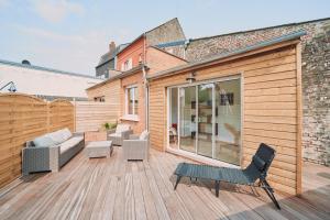 a patio with a couch and chairs on a wooden deck at Villa Bewick-Loft Architecte in Saint-Valery-sur-Somme