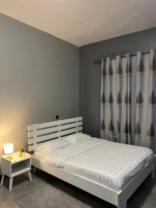a bedroom with a white bed with curtains and a table at Fivas Residences in Arua