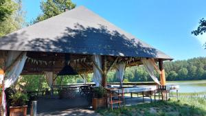 a pavilion with tables and chairs next to a river at Farwne checze in Wdzydze Kiszewskie