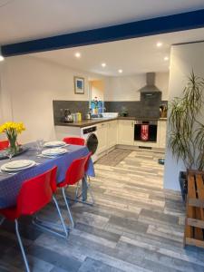 a kitchen with a table and red chairs in a room at The Secret Well in Shaldon