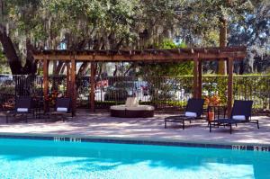 a pool with chairs and a pergola next to a pool at Hilton Garden Inn Tampa East Brandon in Tampa