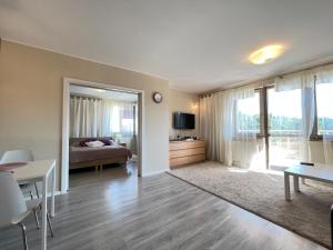 ein Wohnzimmer mit einem Bett und ein Zimmer mit einem Tisch in der Unterkunft Zdrojowa Sun Apartment in Świnoujście