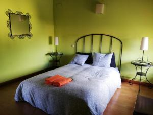 Un dormitorio verde con una cama grande con una toalla naranja. en LA FRAGUA - CASA RURAL EN VILLANUEVA DE GOMEZ (AVILA), en Villanueva de Gómez