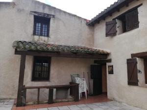 un edificio con porche con mesa y ventana en LA FRAGUA - CASA RURAL EN VILLANUEVA DE GOMEZ (AVILA), en Villanueva de Gómez