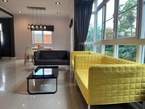 a living room with a yellow couch and a table at Happy home บ้านกว้าง ได้ทั้งหลัง ไวไฟฟรี1000Mbps ใกล้สนามบินสุวรรณภูมิ in Min Buri