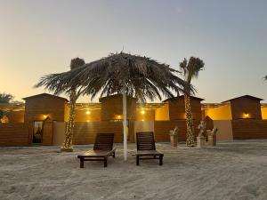 two chairs under a straw umbrella on the beach at Cielo Beach Resort in Al Qaryah