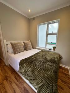 a bedroom with a bed and a window at Camellia Cottage - Courtyard Room in Cape Town