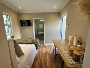 a living room with a table and a bed and a room at Camellia Cottage: Courtyard Room in Cape Town