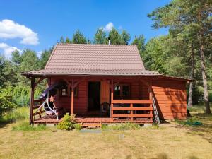 Ce chalet en bois dispose d'une terrasse couverte et d'un toit. dans l'établissement Domek letniskowy, à Skarszewy