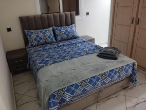 a bed with a blue and white comforter and pillows at AlMohit Larache in Larache