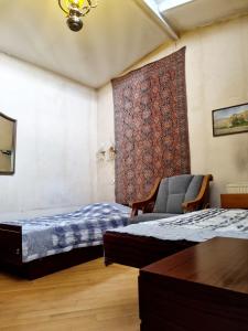 Habitación con 2 camas, silla y alfombra. en Polonia Tbilisi House, en Tiflis