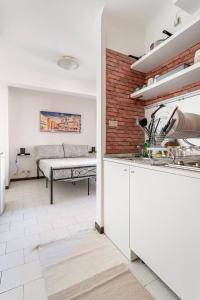 a kitchen with white cabinets and a brick wall at Appartamento Pescherie - Top location in Bologna