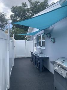a patio with a table and chairs and a blue awning at Private Suite with Private Gym&Patio, Minutes to Beaches, Up to 4 Guests in Largo