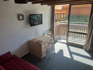 um quarto com uma mesa, uma televisão e uma varanda em Orcières-Merlette le Panoramic em Orcières