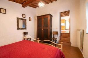 een slaapkamer met een rood bed en een houten kast bij Tenuta La Cella - Grande Appartamento in Arezzo