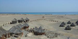 a group of huts in the sand on a beach at Deep South Hostel in Marsa Alam City