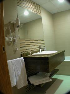 a bathroom with a sink and a mirror and towels at Hotel Portal Del Matarraña in Valjunquera