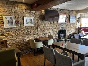 um restaurante com mesas e cadeiras e uma parede de pedra em Crown & Anchor em Grantham