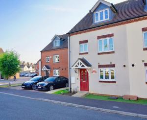 a white house with a red door on a street at Super Quiet 4 Bed Family House in Gravesend in Kent