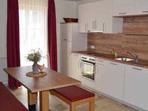 eine Küche mit weißen Schränken und einem Holztisch in der Unterkunft Libelle in Colmberg
