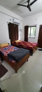 a bedroom with two beds and a ceiling fan at Kalawati Niwas in Bodh Gaya