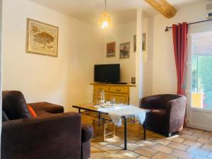 ein Wohnzimmer mit einem Tisch und Stühlen sowie einem TV in der Unterkunft La Pitchoune : Gîte aux pieds des Alpilles in Mouriès