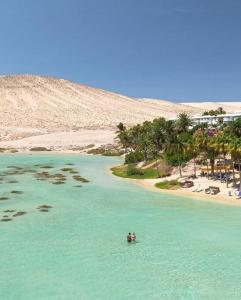 two people in the water near a beach at El Caseton in Costa Calma