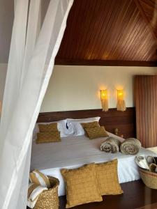 a bedroom with a large white bed with wooden ceilings at Kuarasy Boutique Hotel Japaratinga in Japaratinga