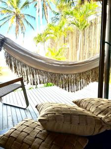 雅帕拉廷加的住宿－Kuarasy Boutique Hotel Japaratinga，棕榈树甲板上的吊床和椅子
