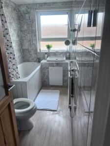 a bathroom with a toilet and a tub and a sink at Parsonage Leys in Harlow