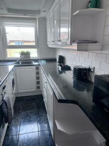 a kitchen with white cabinets and a black counter top at Parsonage Leys in Harlow