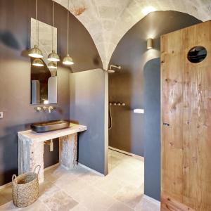 een badkamer met een wastafel en een houten deur bij Bambarone La Masseria in Fasano