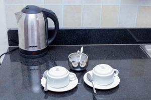 a counter top with two cups and a coffee maker at LA BREZI SUITES in Kampala