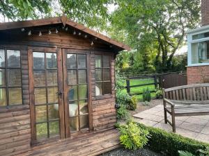 a wooden shed with glass doors and a bench at 5A - ‘Your Place’ A Unique Space to make your own. in Elloughton