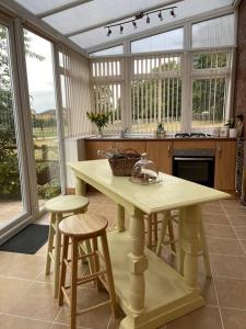 cocina con mesa y taburetes en una habitación con ventanas en 5A - ‘Your Place’ A Unique Space to make your own., en Elloughton